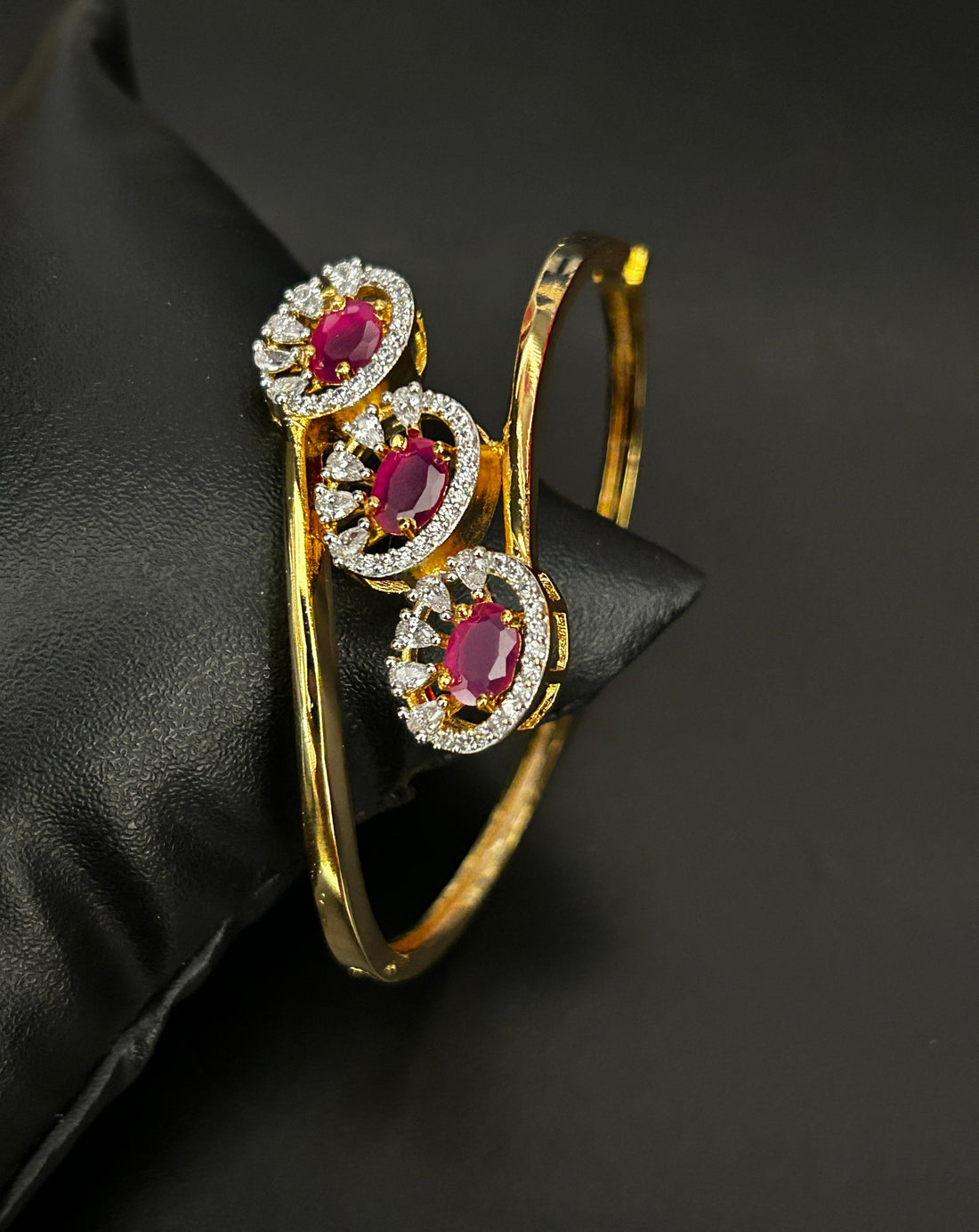 Gold bracelet with red gemstones on a black background