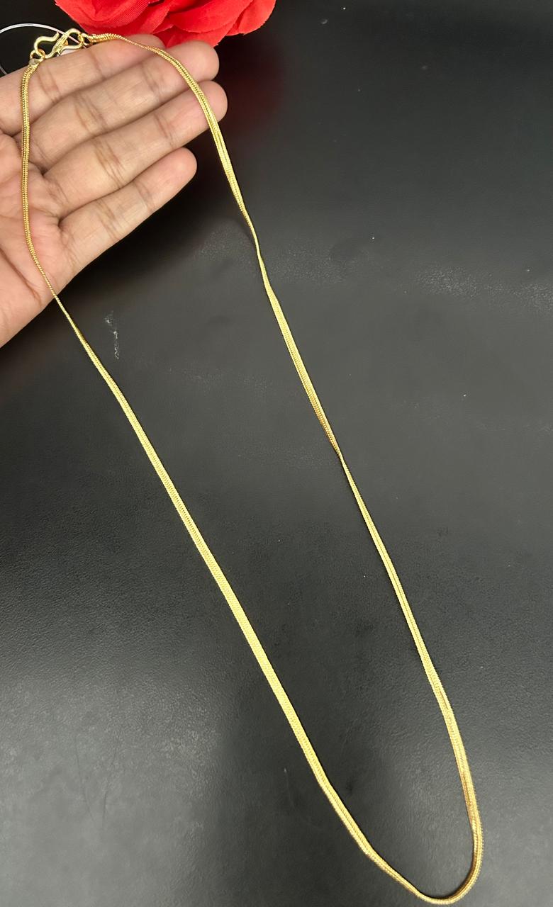 Gold chain held by a hand against a dark background