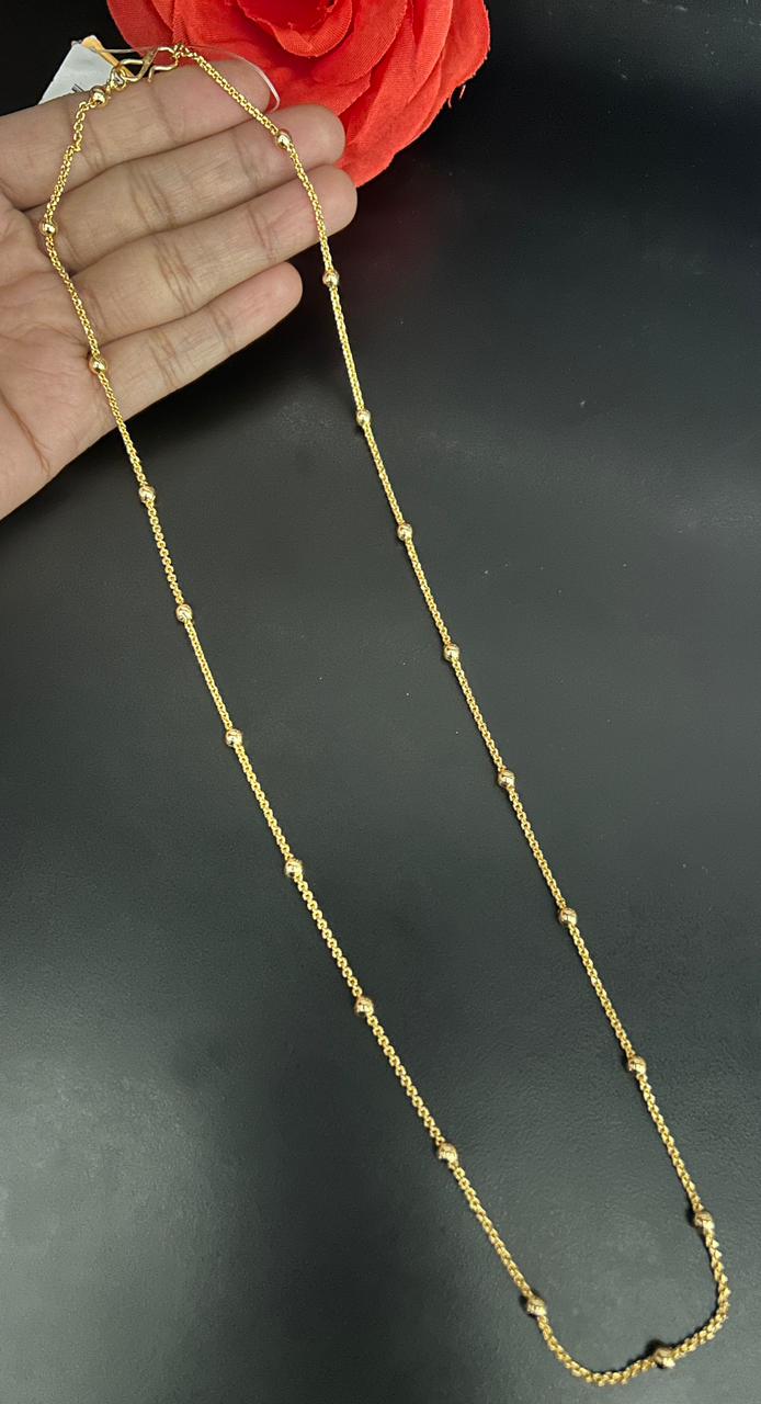 Gold chain held by against a dark background