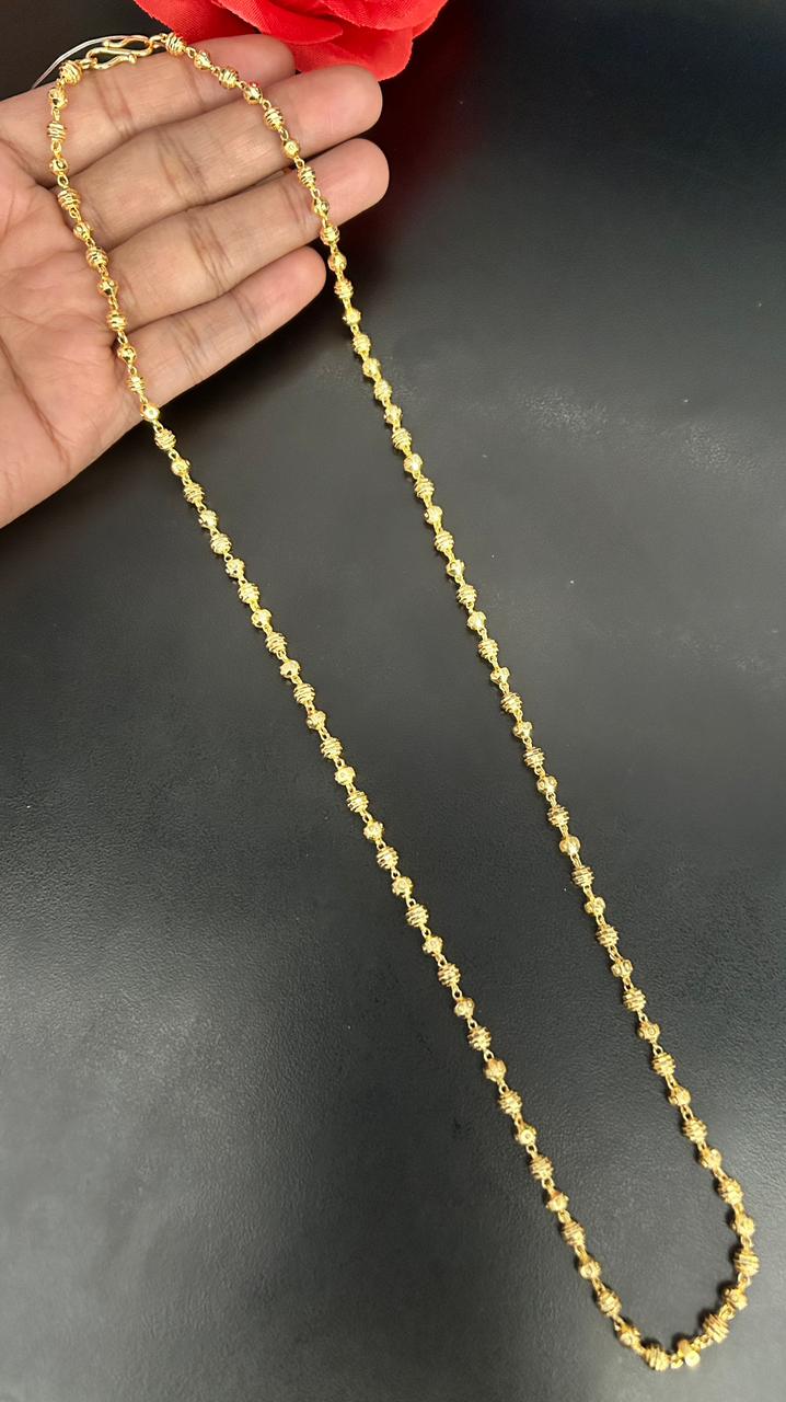 Gold chain held by and against a dark background