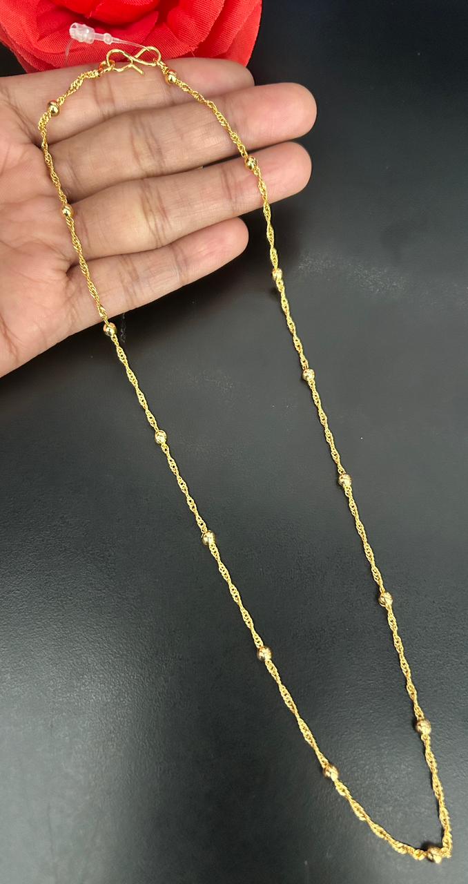 Gold chain held by hand on a dark background