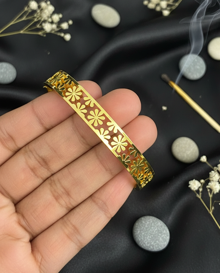 Gold decorative object held in a hand with a black fabric background