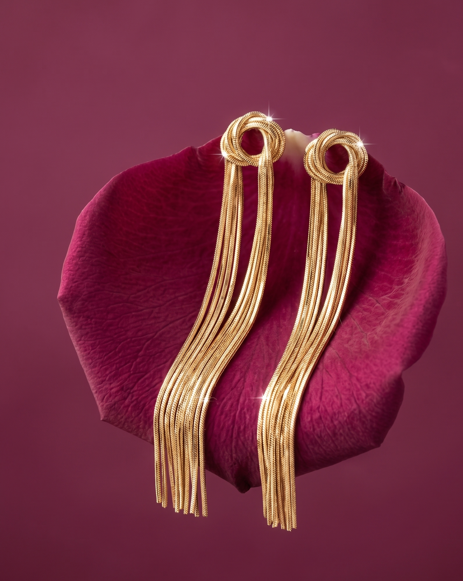 Gold earrings on a pink flower petal