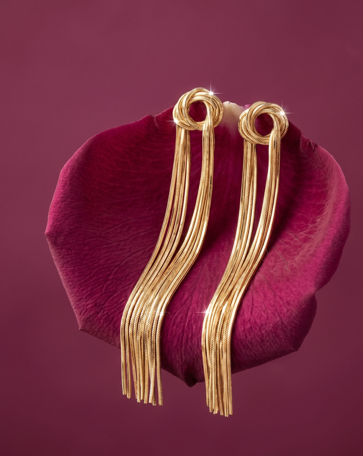 Gold earrings on a pink flower petal