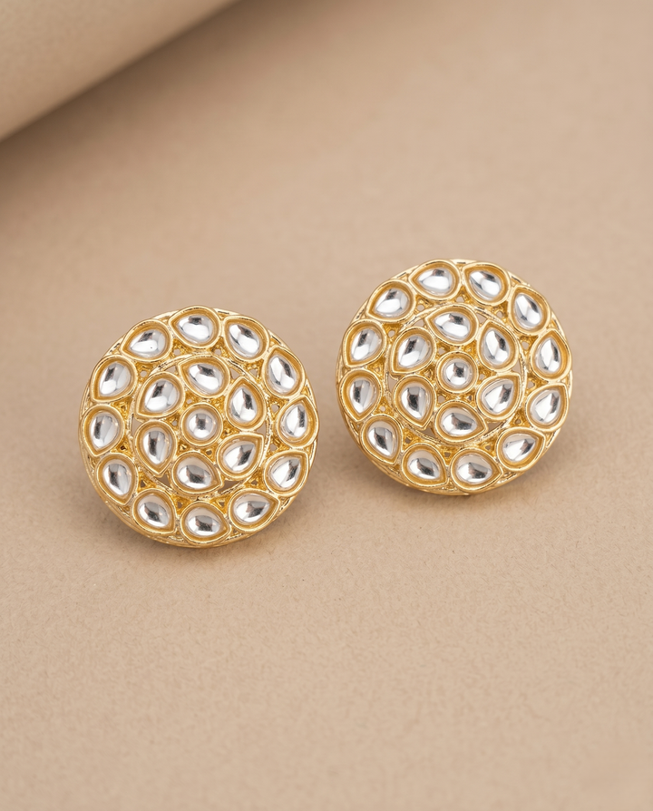 Gold earrings with a bead-like design on a beige background