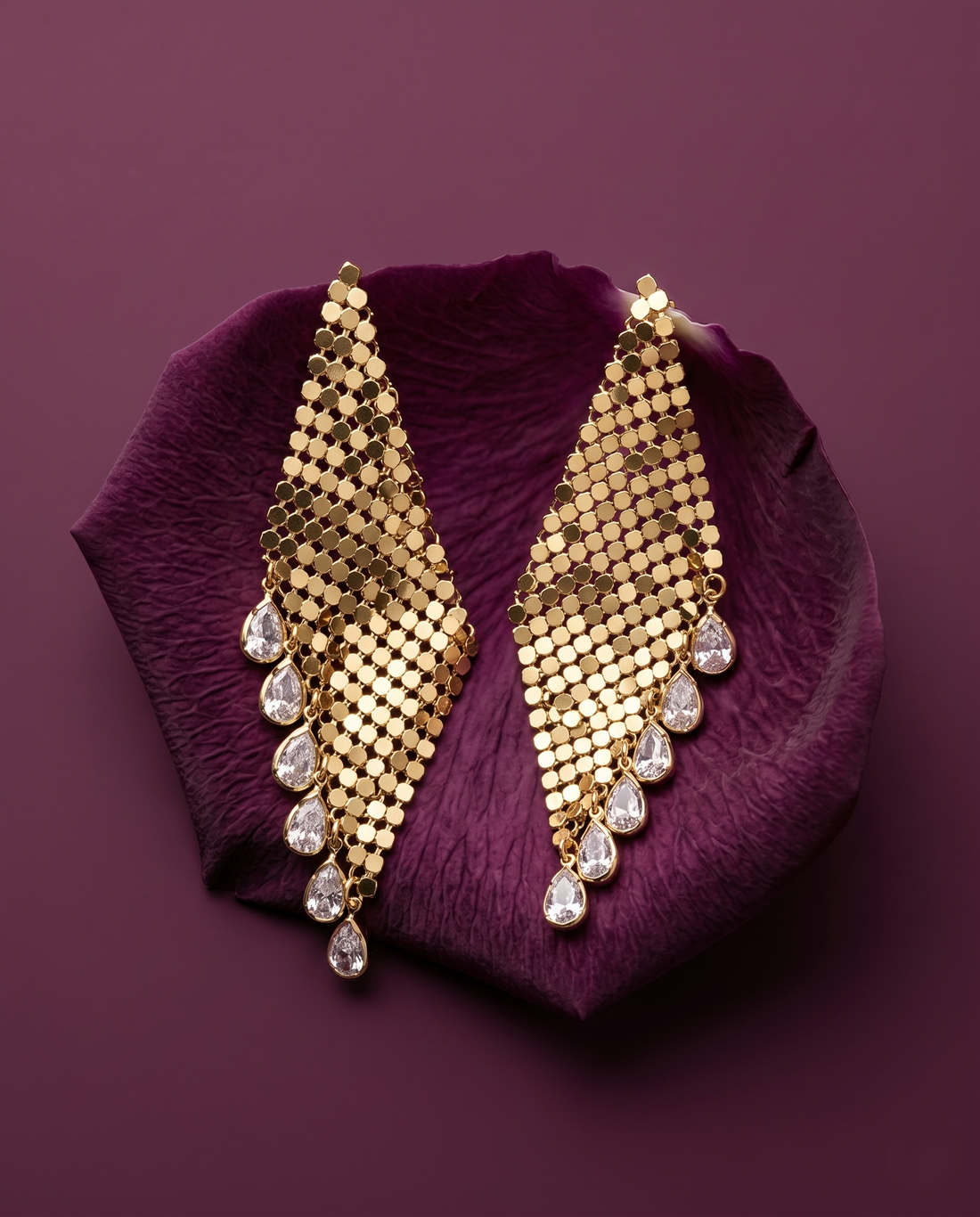 Gold earrings with diamond-like stones on a purple petal
