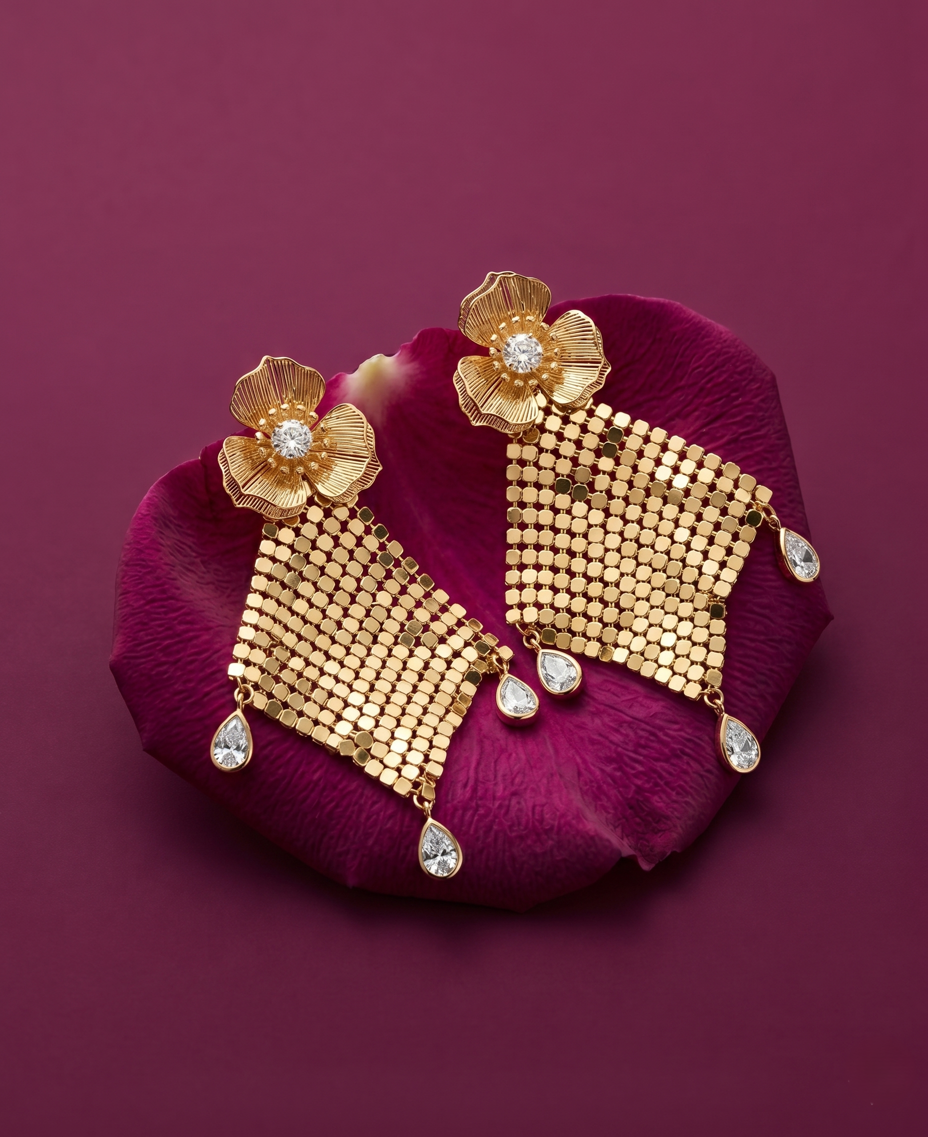 Gold earrings with floral designs on a purple petal