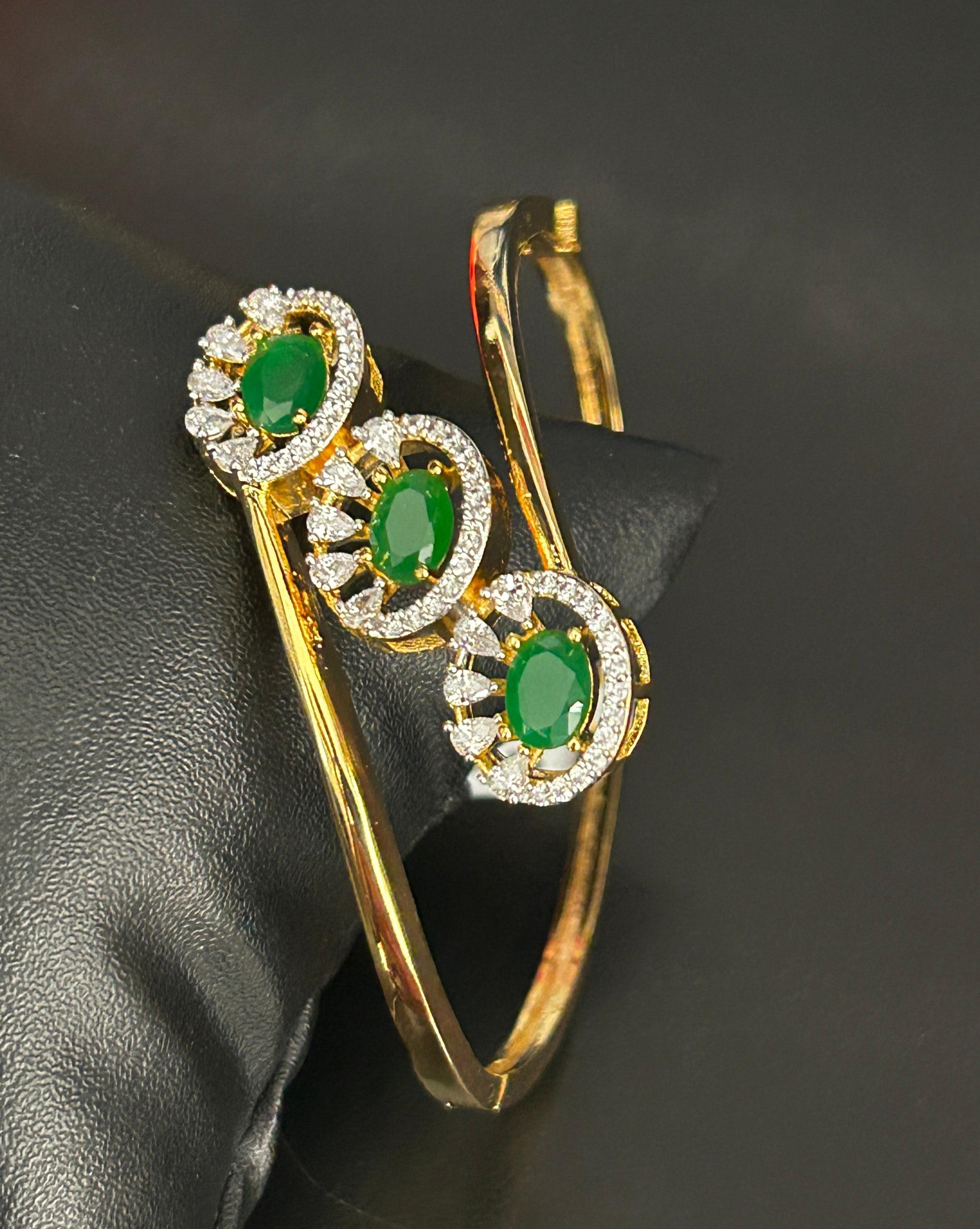 Gold earrings with green gemstones on a black background