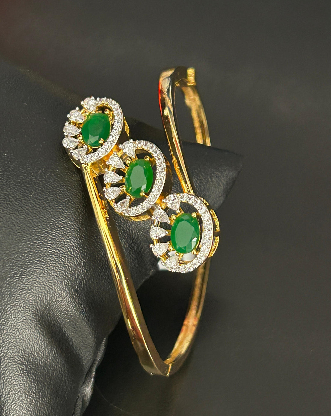 Gold earrings with green gemstones on a black background