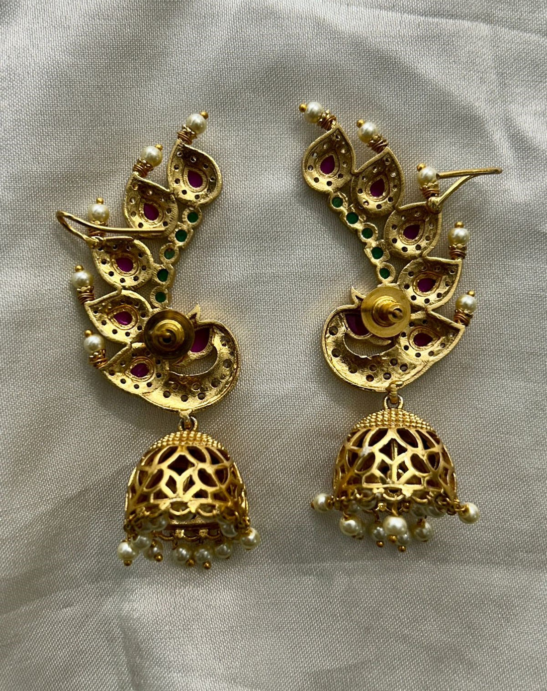Gold earrings with intricate designs on a light gray background