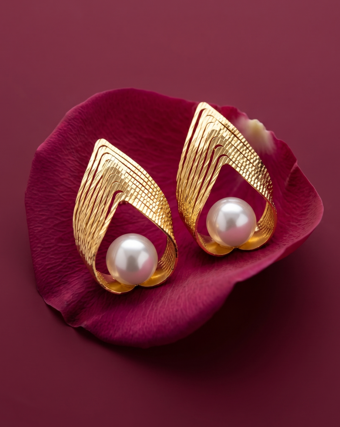 Gold earrings with pearls on a pink flower petal