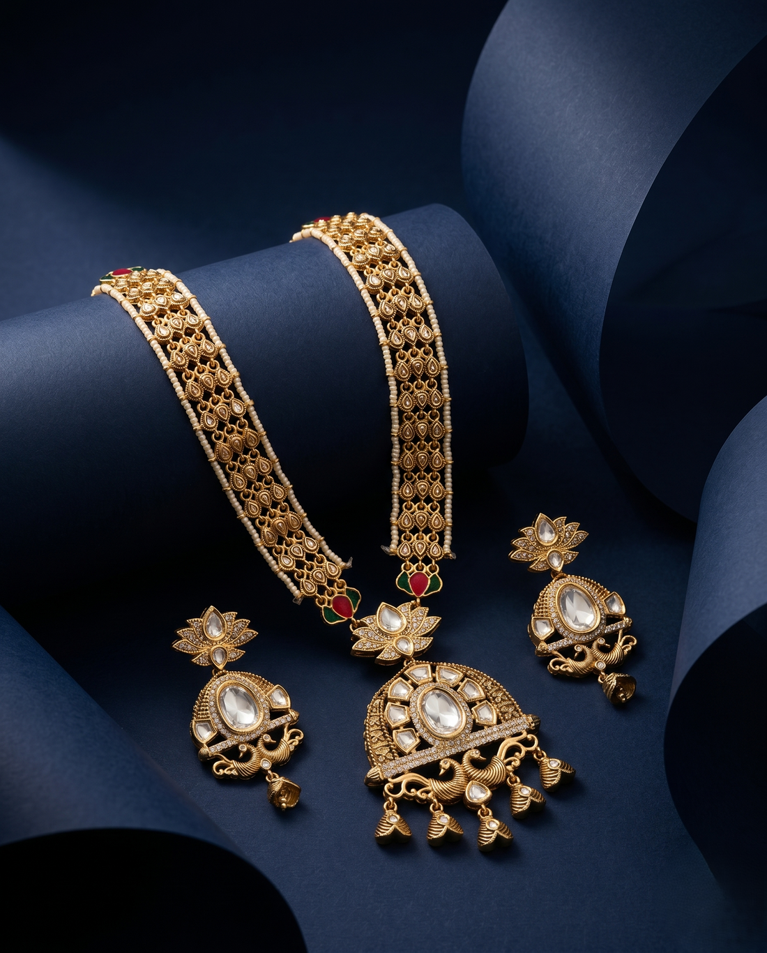 Gold jewelry set including necklace, earrings, and bangles on a dark blue background