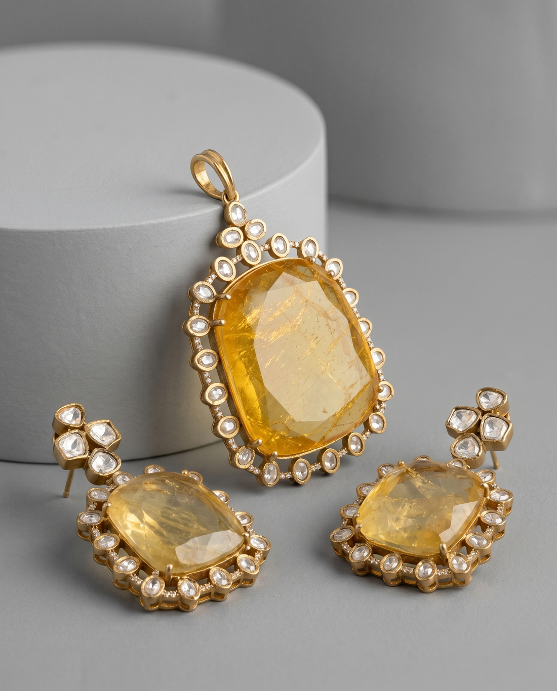 Gold jewelry set with yellow gemstones on a gray background
