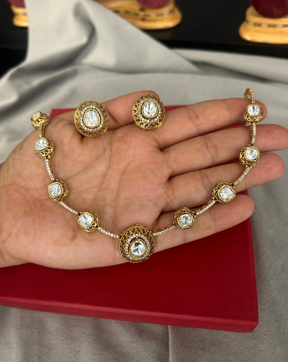 Gold necklace and earrings on a hand with a red box in the background