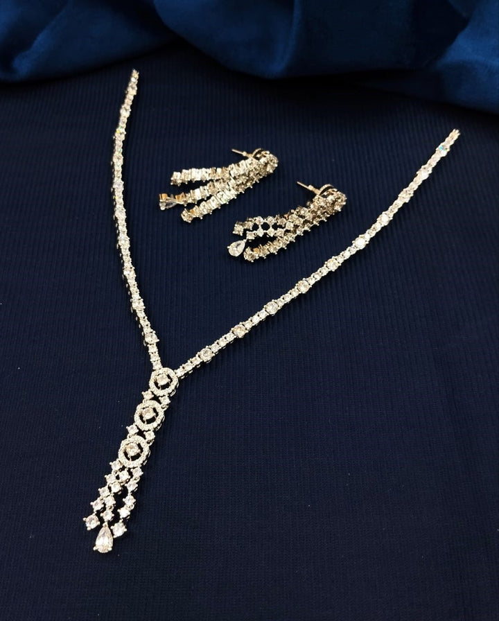Gold necklace and earrings on a dark blue fabric background
