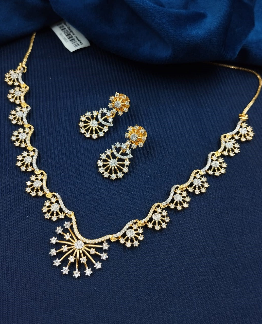 Gold necklace and earrings set on a blue fabric background