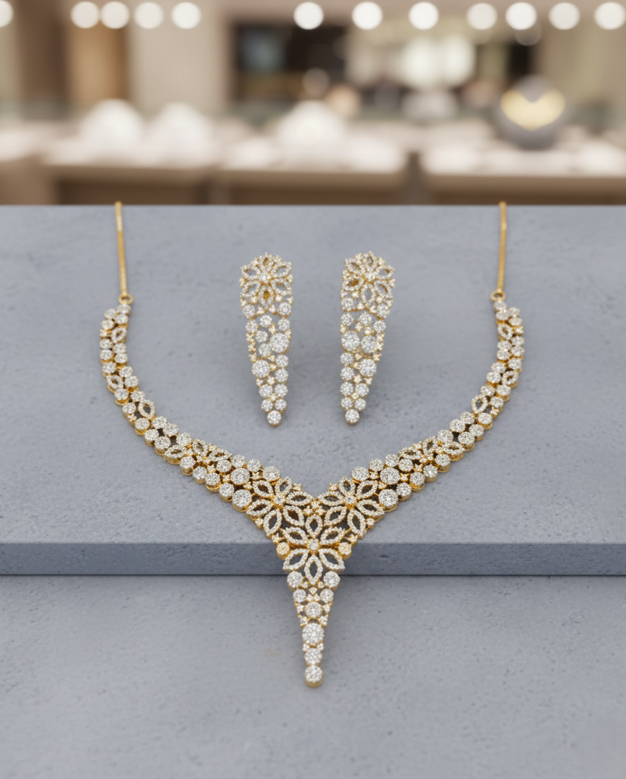 Gold necklace and earrings set on a gray surface with a blurred background