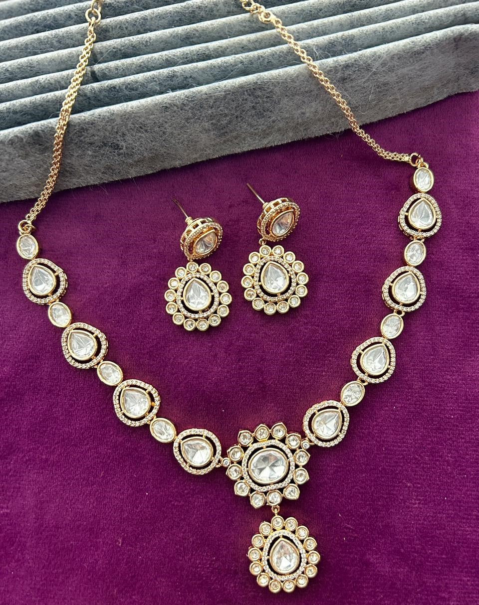 Gold necklace and earrings set on a purple surface