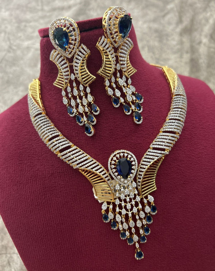 Gold necklace and earrings with blue stones on a mannequin bust.