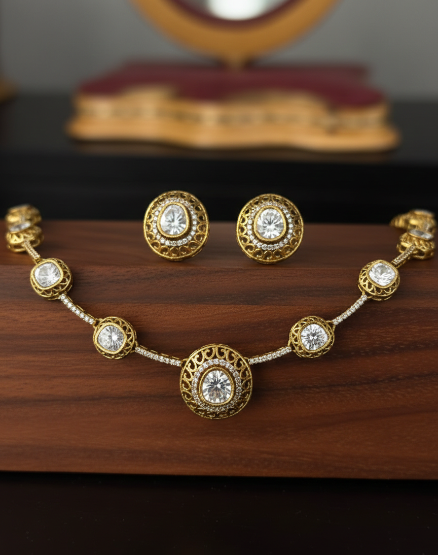 Gold necklace and earrings with clear stones on a wooden surface