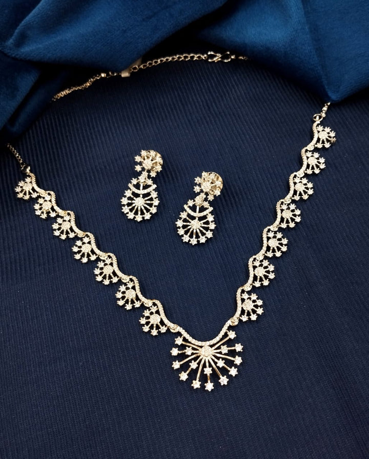 Gold necklace and earrings set on a blue fabric background