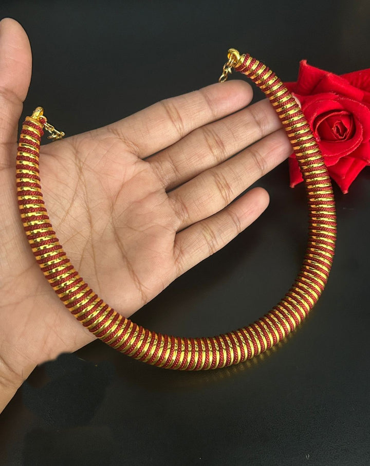Gold necklace being held on a hand with a dark background