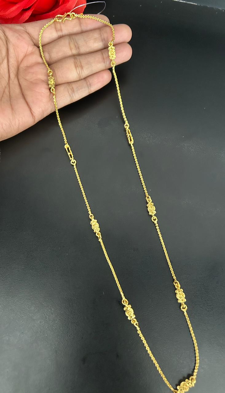 Gold necklace held a hand against a dark background