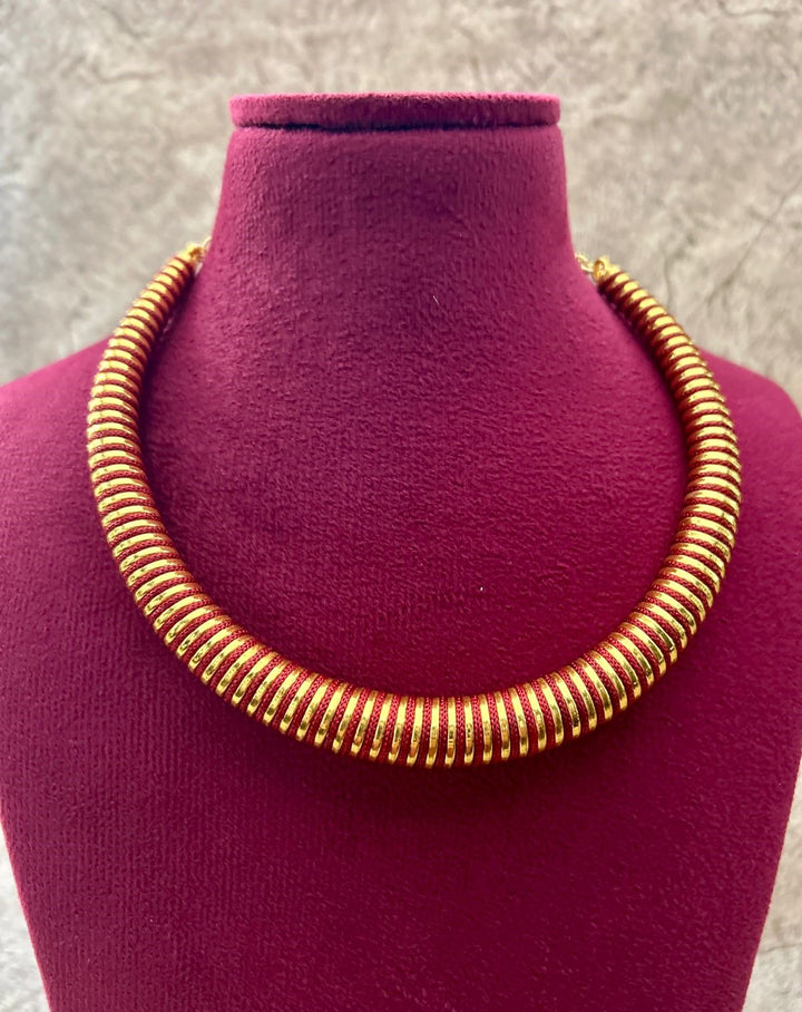 Gold necklace on a purple mannequin bust against a gray background