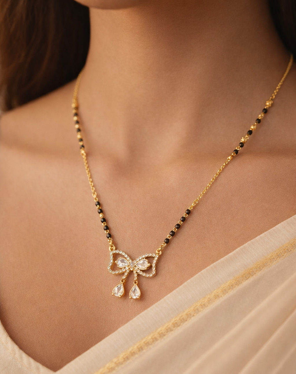 Gold-finish mangalsutra necklace featuring a bow-shaped diamond-style pendant