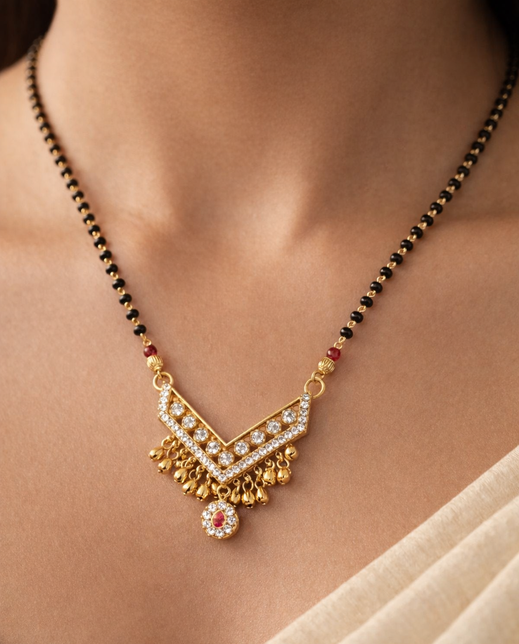 Gold-polish mangalsutra featuring a stone-studded V-shaped pendant with hanging drops
