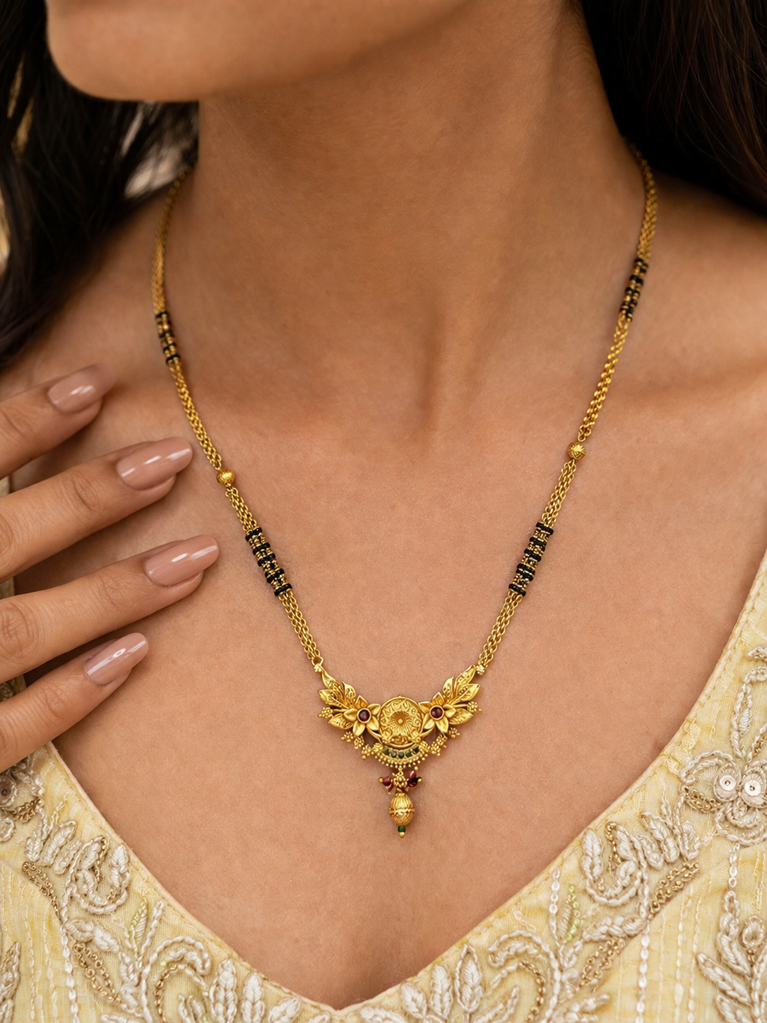 Gold necklace with floral pendant worn by a person