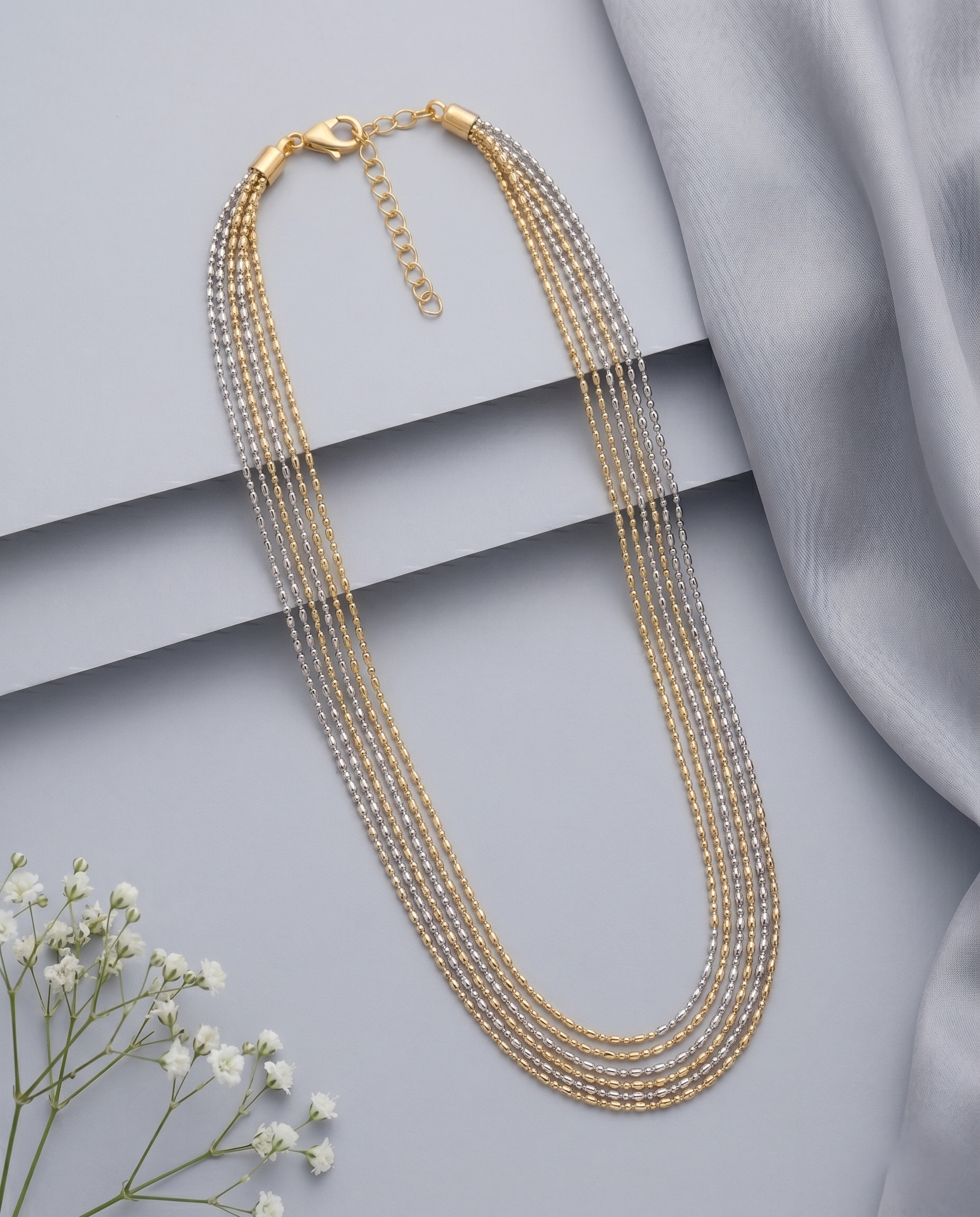 Gold necklace with multiple strands on a light gray background