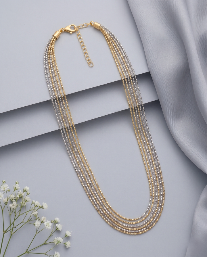 Gold necklace with multiple strands on a light gray background