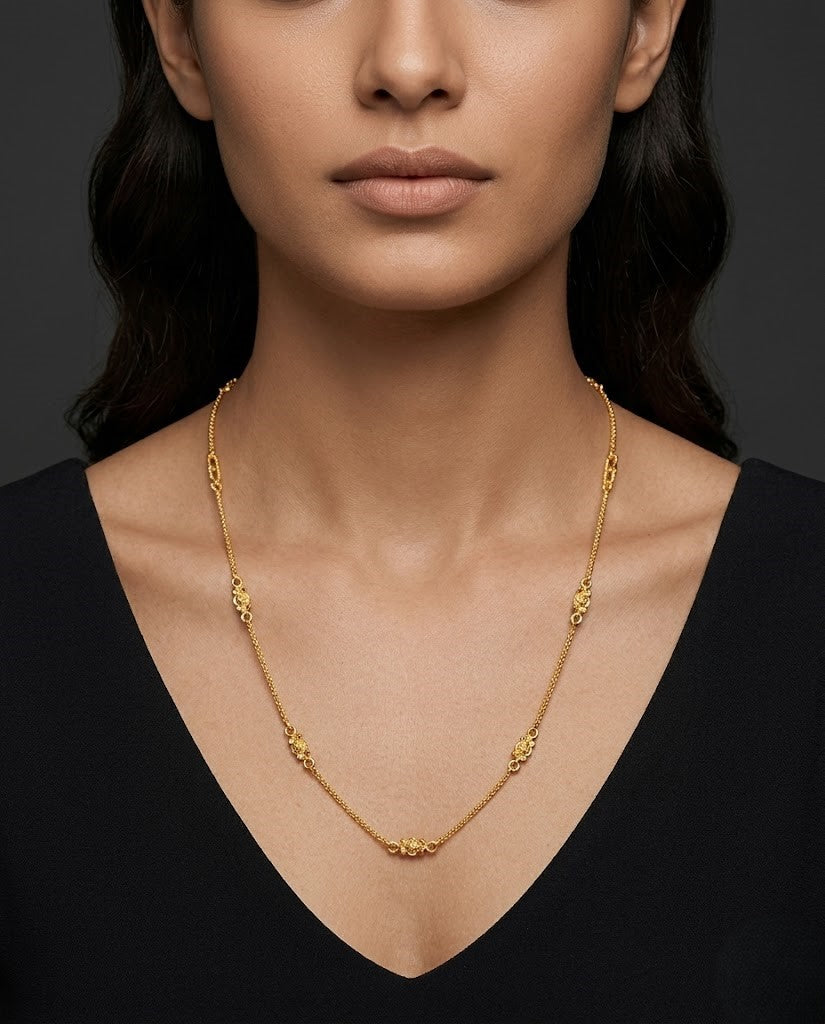 Gold necklace worn a person against a dark background