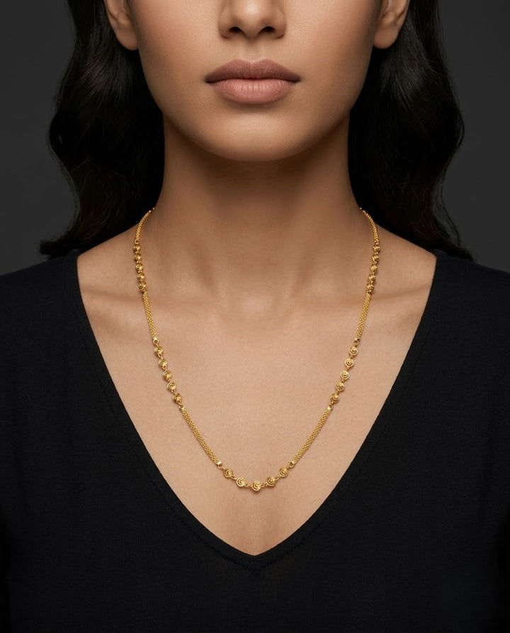 Gold necklace worn by a person against a dark background