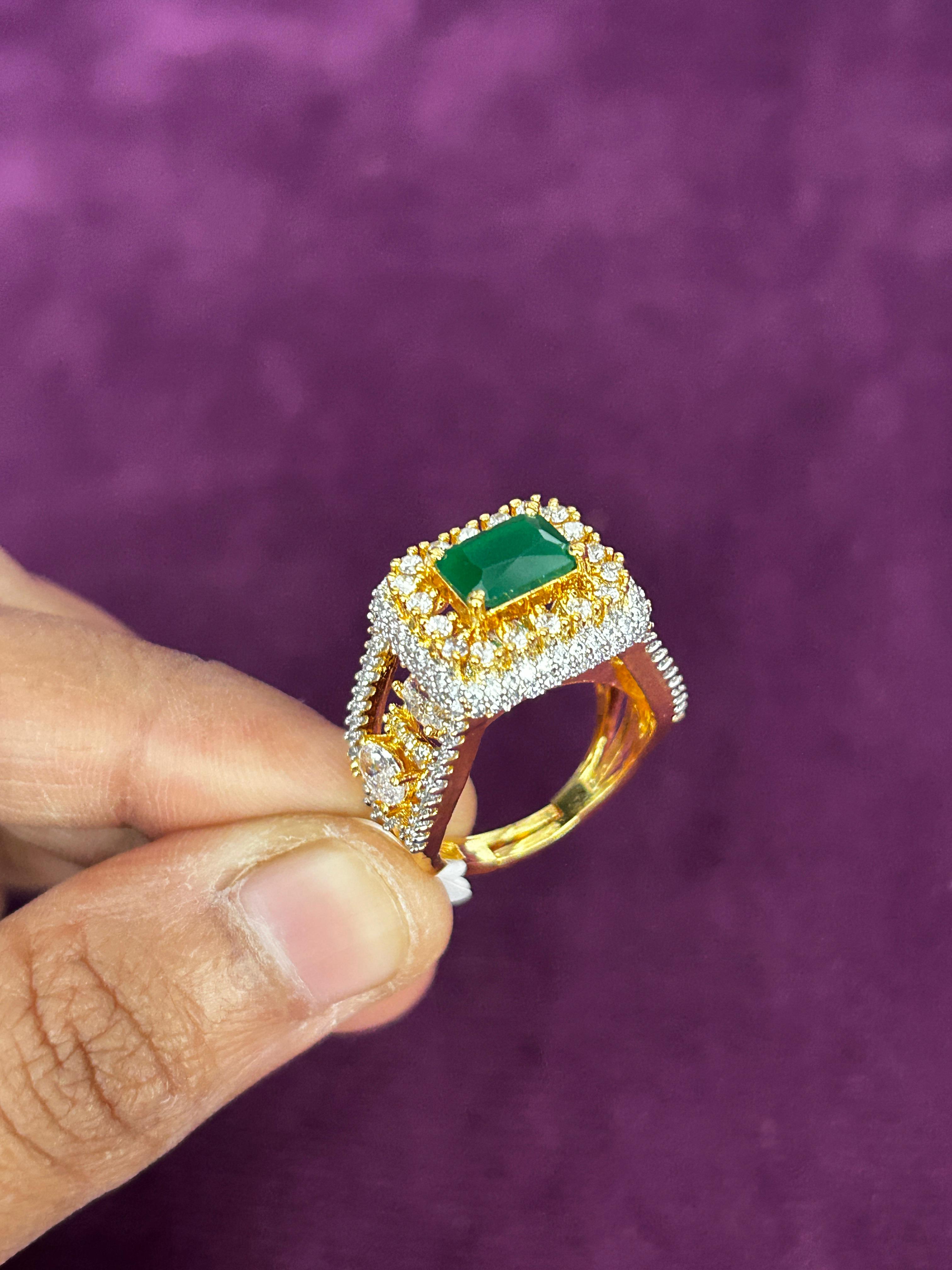Gold ring with a green gemstone held by a hand against a purple background