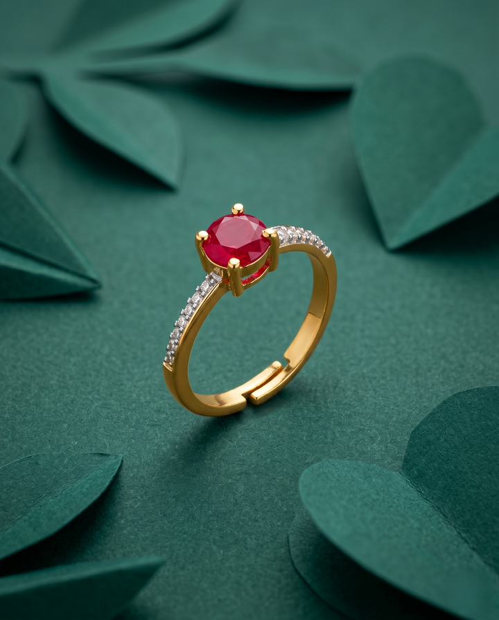 Gold ring with a red gemstone on a green leafy background