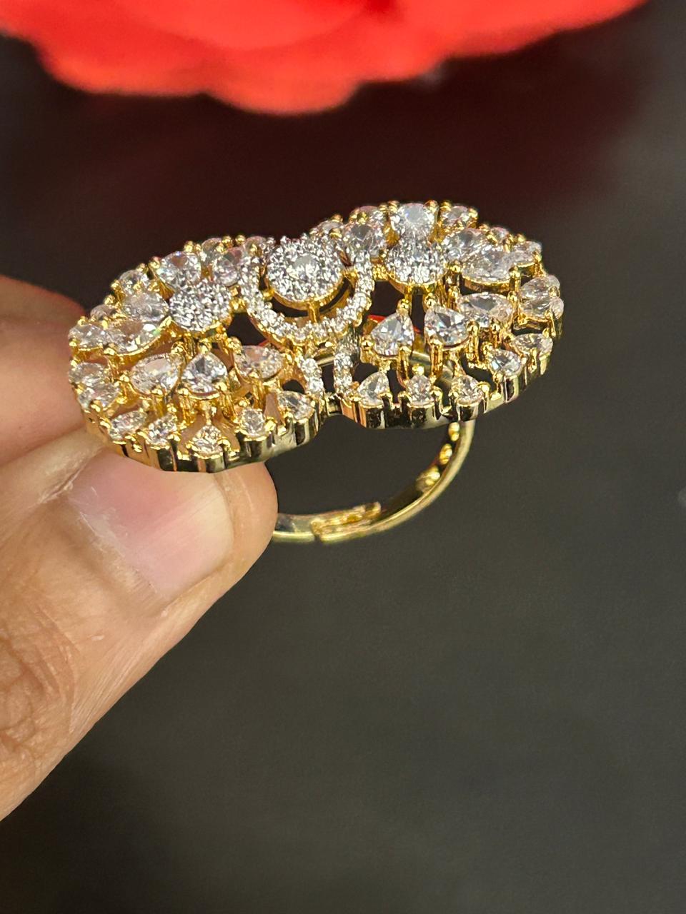 Gold ring with diamond accents held by a hand against a dark background