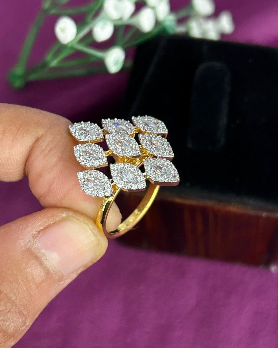 Gold ring with diamond leaves held by a hand on a purple surface