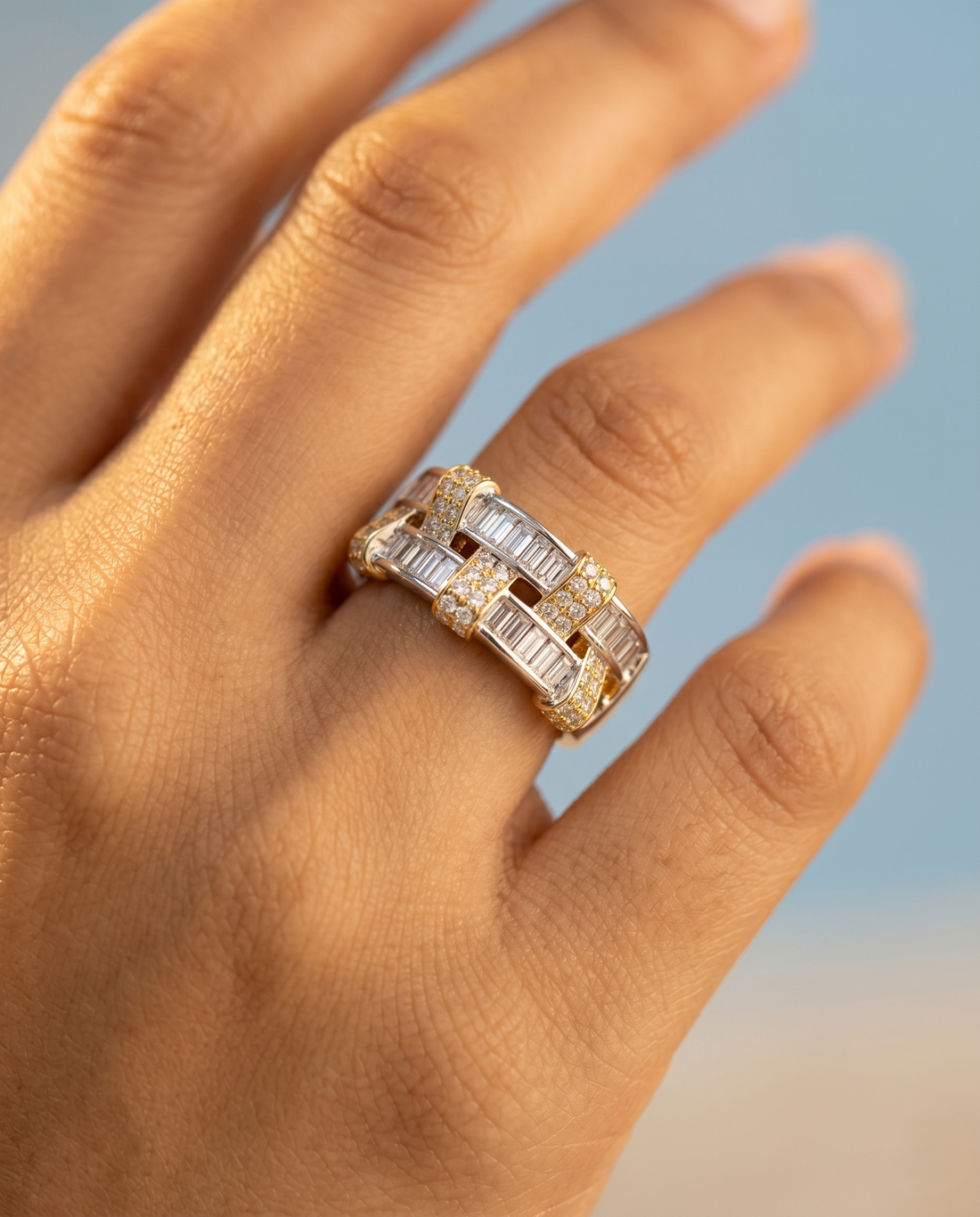 Gold ring with diamonds on a hand against a blurred natural background