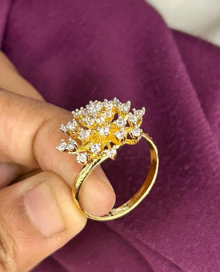 Gold ring with diamonds held by a hand against a purple fabric background