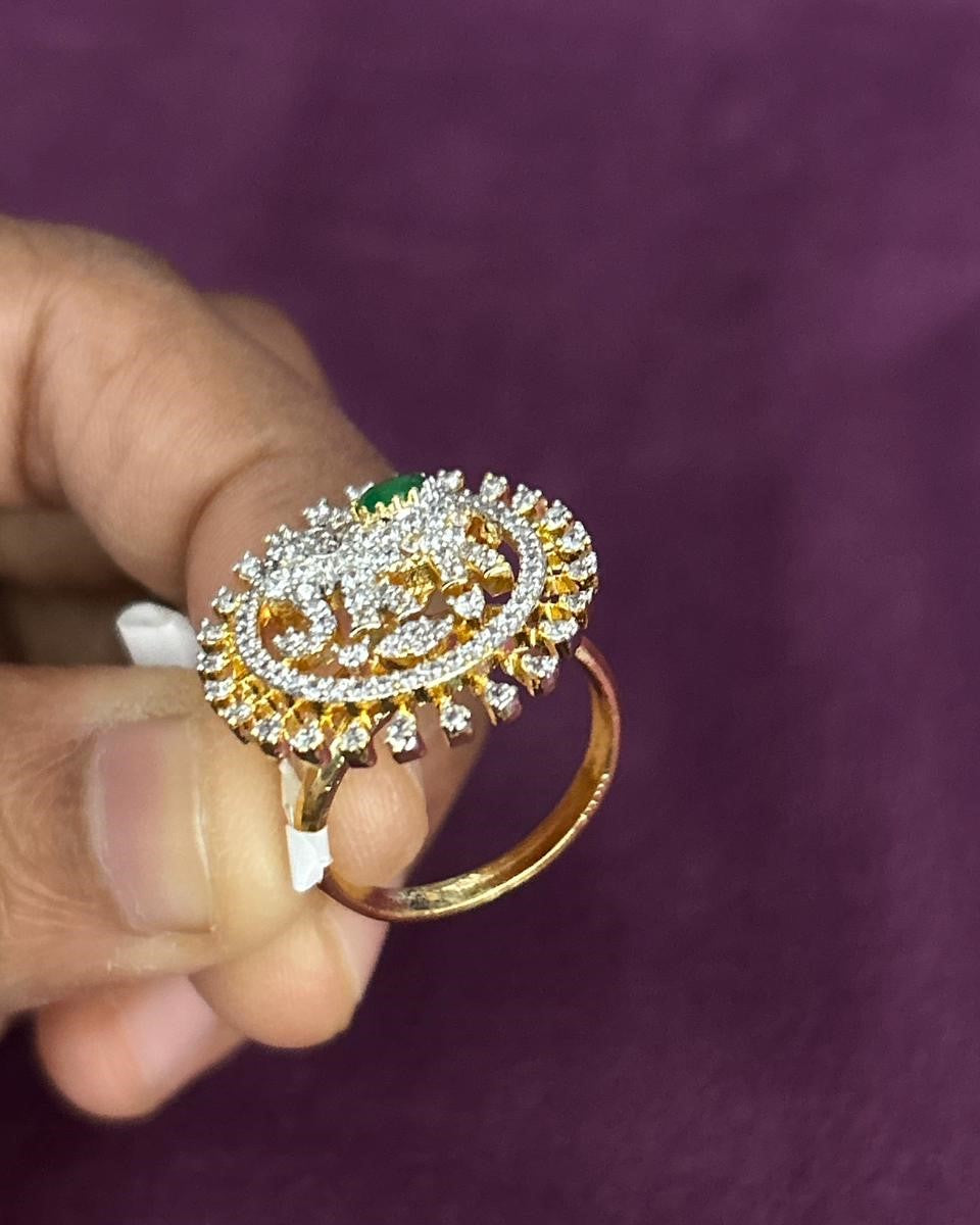Gold ring with gemstones held by a hand against a purple background
