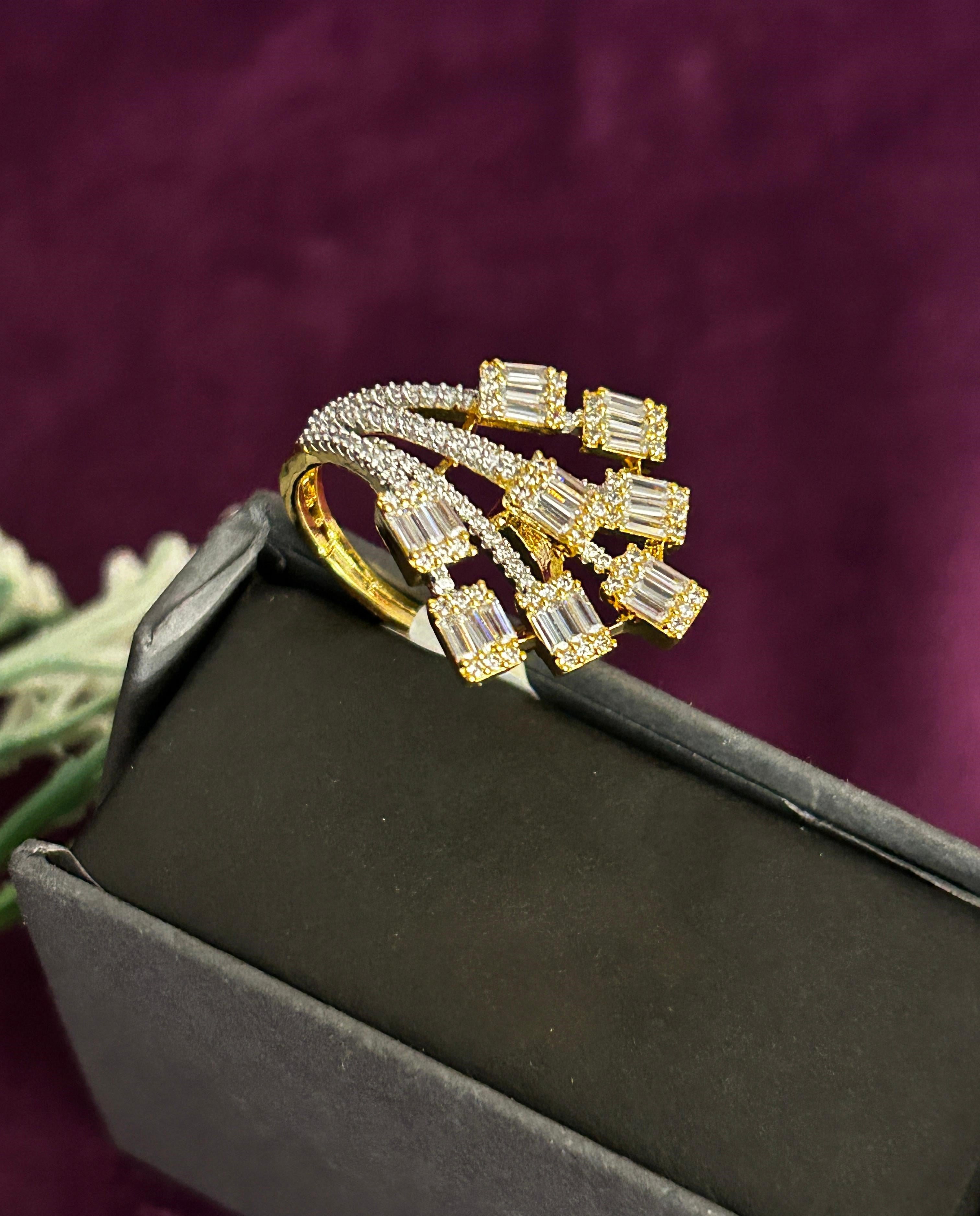 Gold ring with gemstones on a black box against a purple background