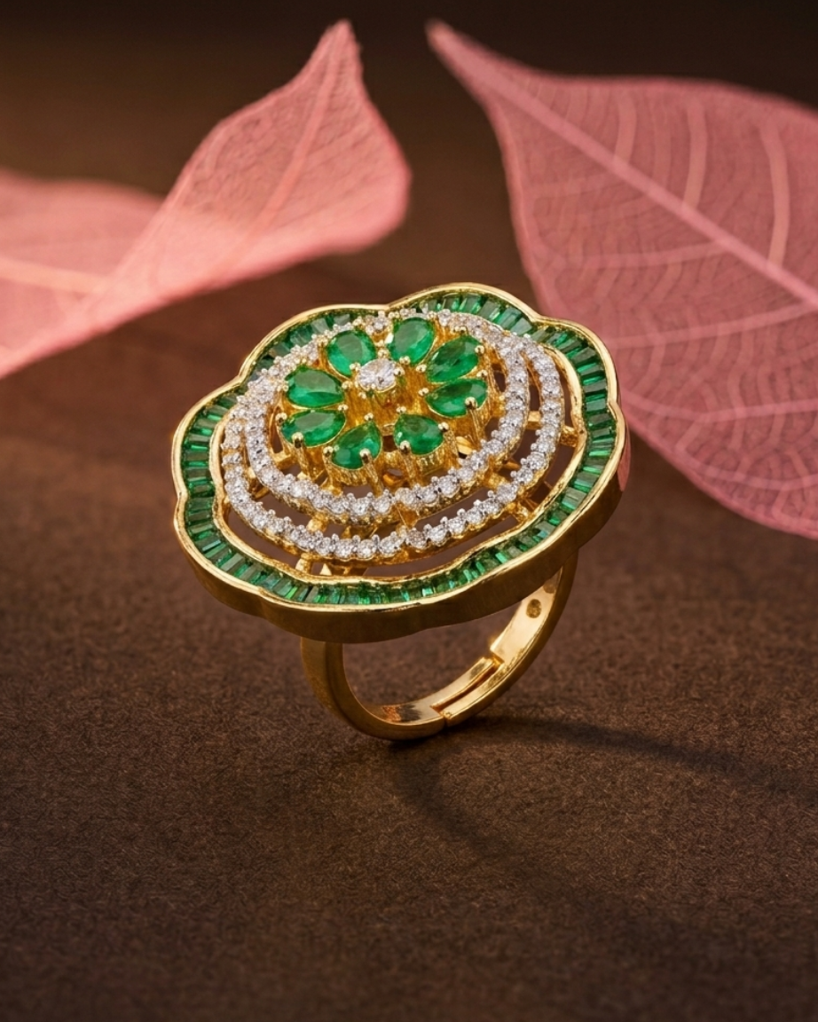 Gold ring with green and white gemstones on a brown background with pink leaves.