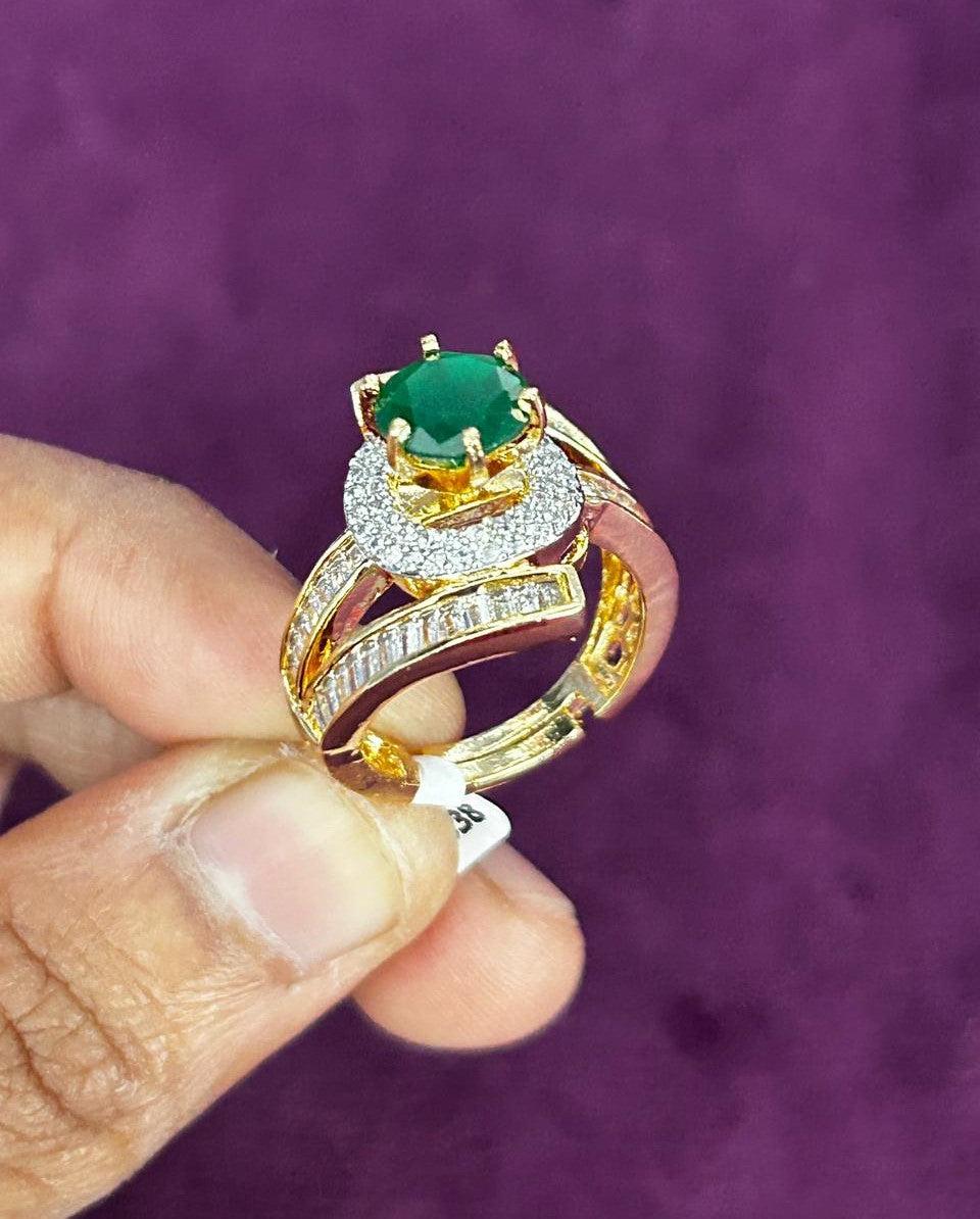 Gold ring with green gemstone held by a hand against a purple background