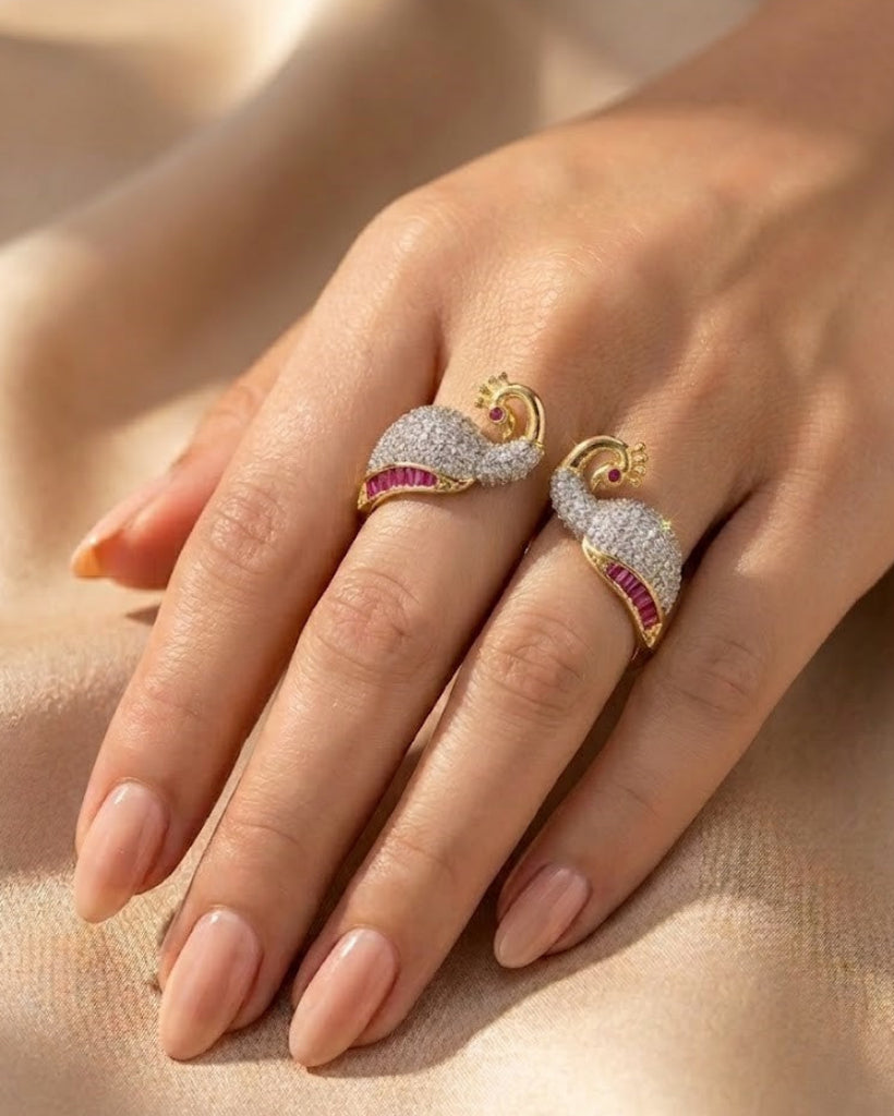 Gold rings with gemstones on a hand against a beige background