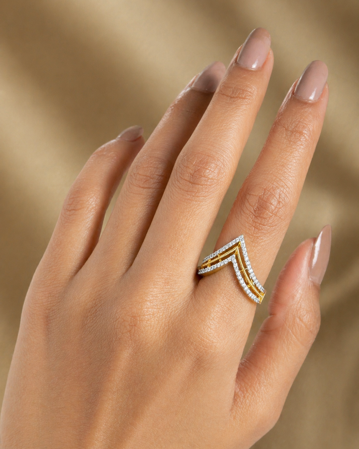 Hand wearing a gold and diamond ring against a beige background
