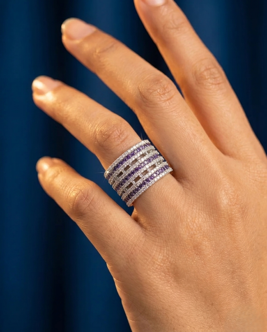 Hand wearing a stack of diamond rings against a dark blue background