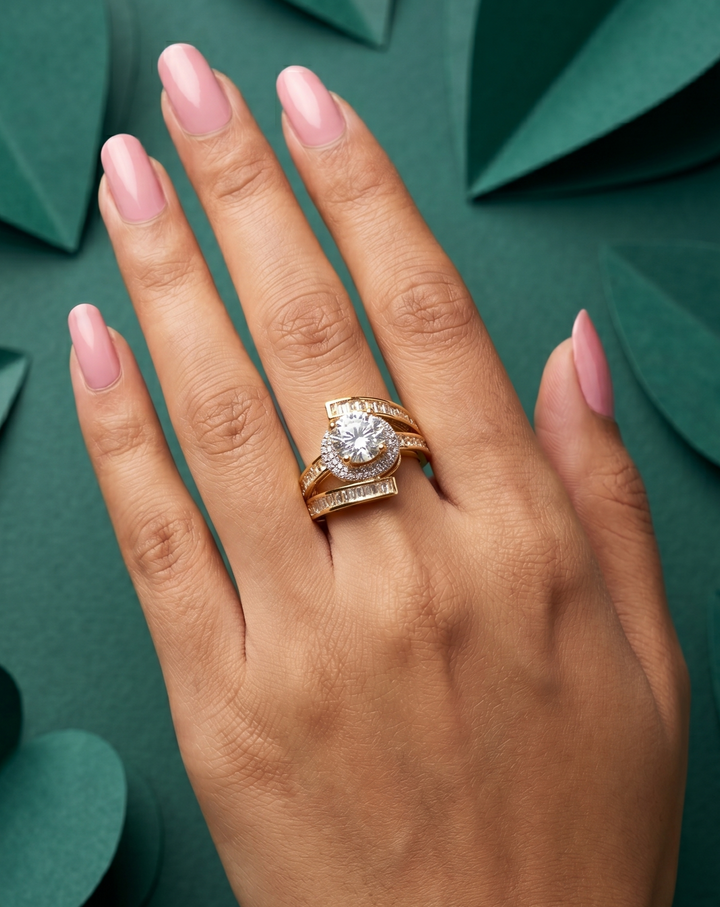 Hand wearing a gold ring with a diamond on a green leafy background