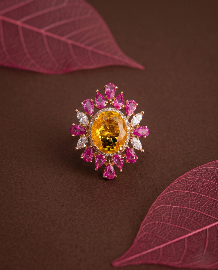 Jewelry ring with pink and yellow gemstones on a brown background with red leaves.